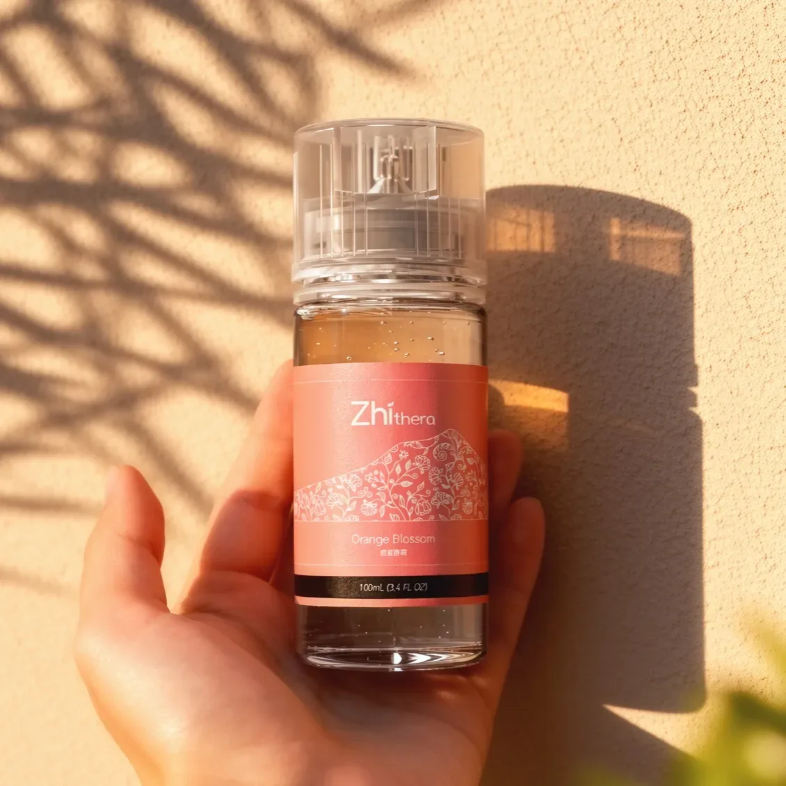 Hand holding a Zhithera Orange Blossom fragrance oil bottle in sunlight